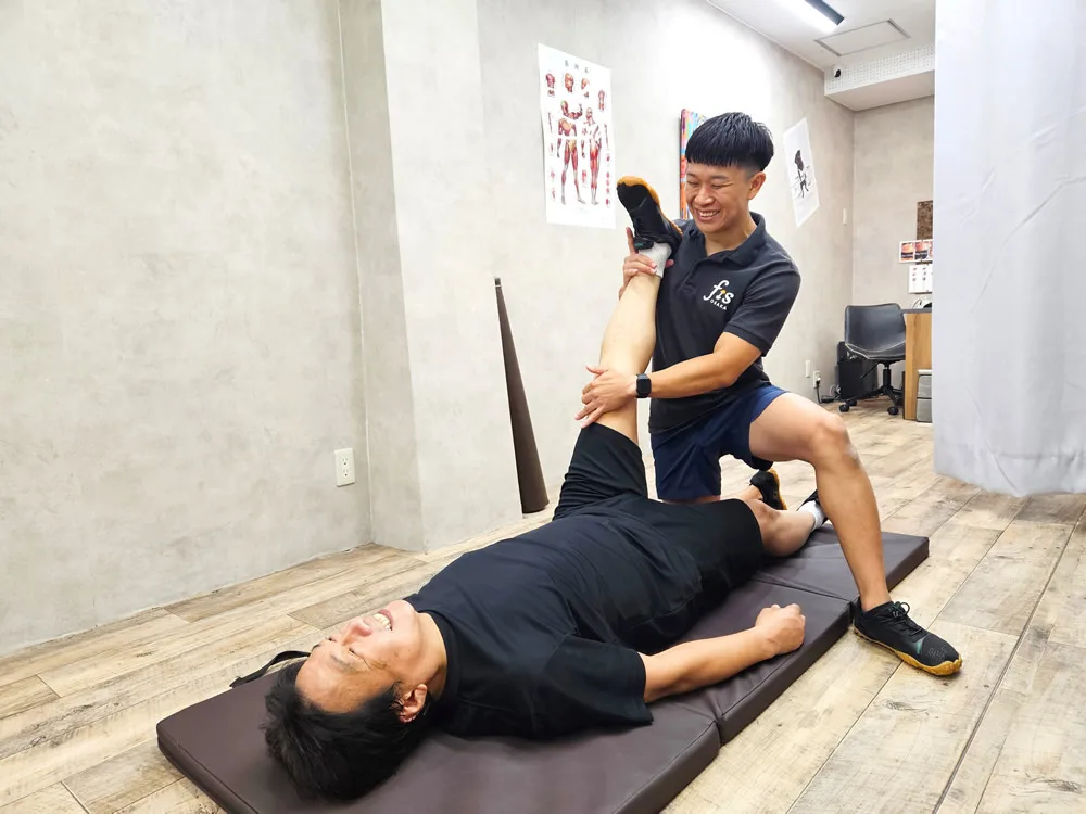 マットの上で脚のストレッチを受けているところ